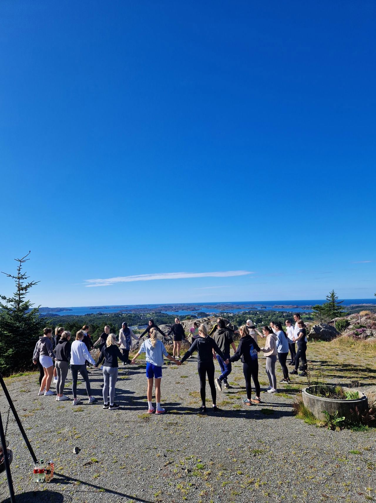 Elevar held hender og står i ring på ein grusplass ute i naturen