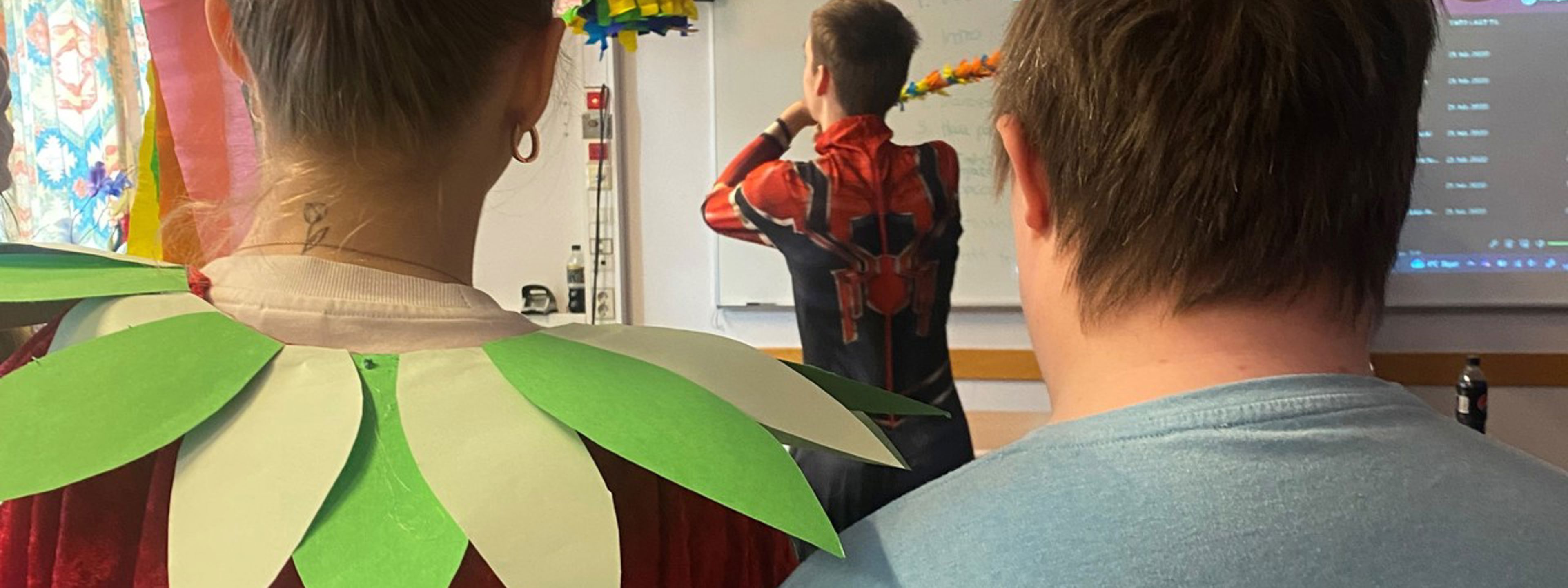 Gut i Spider Man-kostyme slår på pinjata. Elev frå 2BUa og elev frå HTH ser på.