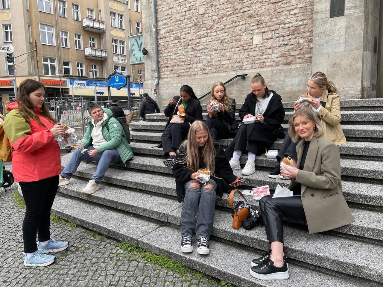 Elevane og rektor Rebecca sit på ei trapp og et kebablunsj