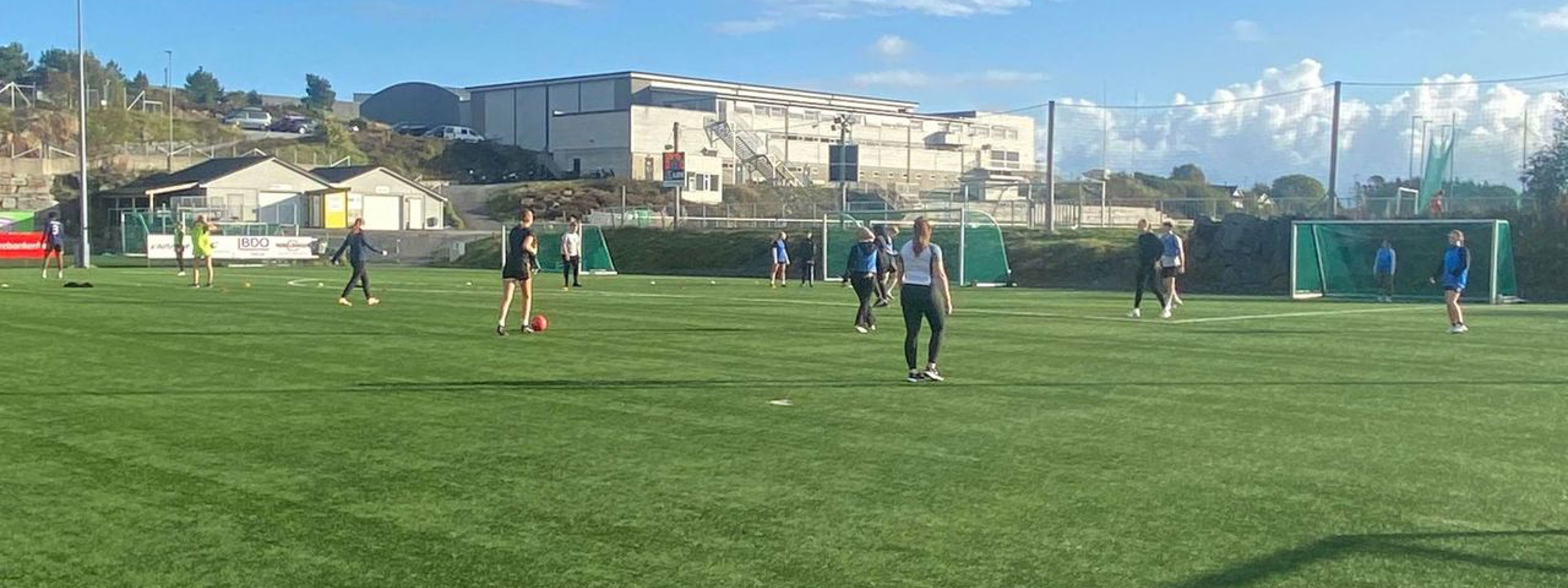Elevar speler fotball på kunstgrasbanen.