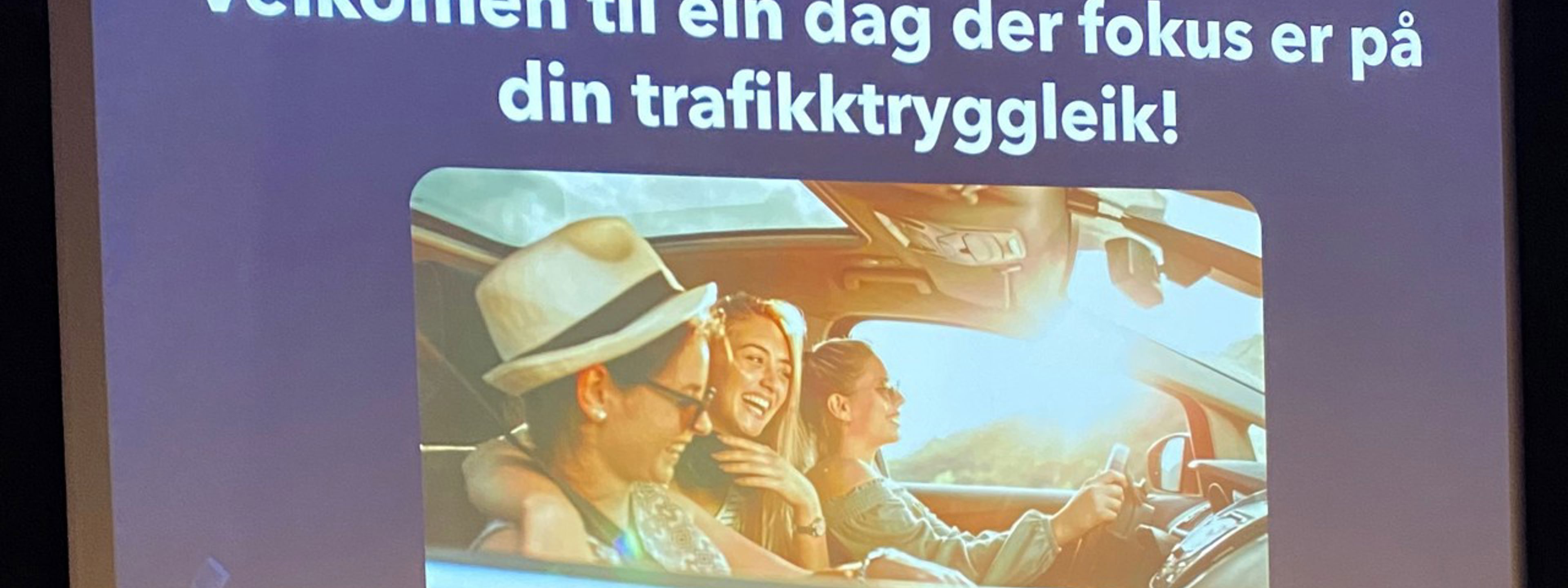 Bilde av ein powerpoint der det står "Velkomen til ein dag der fokus er på din trafikktryggleik". Under er det bilde av unge menneske i ein bil på ein solfylt dag.